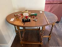 Top-down angle showing the table fully extended with both leaves up. Several small items sit on the tabletop.