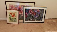 Three framed floral artworks displayed together on carpet, showing relative size and framing styles.