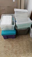 Overall stack of various plastic storage bins on carpeted floor.