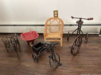 Three metal bikes, small red wheelbarrow, and small wicker chair arranged on floor