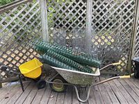 Photo of wheelbarrow with rolls of green plastic fencing and grey chicken wire inside
