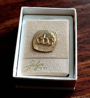 Front view of 10 kt gold CBC pin mounted on soft insert inside original box with "Jolyn 10 kt" inscription.