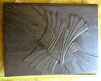 Top view of the closed large leather photo album showing the embossed abstract design on the brown leather cover.