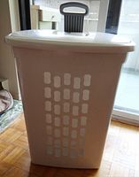 Front view of the large white Sterilite laundry bin showing vented side and wheels at base.