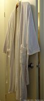 Full view of the vintage Caulfeild Canada terrycloth bathrobe hanging on a door, showcasing the long length, sleeve style, and front pockets.