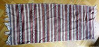 Full view of the woven table runner laid flat showing striped pattern and fringe at ends