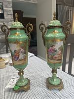 Pair of urn vases on table showing overall form, lids, handles and bases.