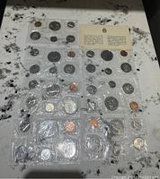 Overview of seven Canadian mint sets sealed in cellophane with informational cards showing visible coin designs including cents, nickels, dimes, quarters, and larger dollar coins.