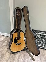 Full view of the Fender acoustic guitar in its open hard case, showing natural wood finish and black pickguard.