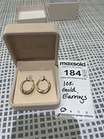 Pair of tri-colour 10k gold hoop earrings inside a beige jewellery box, with 'CHARM' branding on inside lid. Original box included, earrings have yellow, white and rose gold sections.