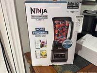 Front of box showing Ninja Professional Plus Blender model with Auto-IQ and 1400 peak watts. Image of blender with berries inside pitcher.