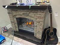Front view of fireplace with flame effect next to a guitar