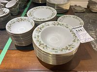 Stack of bread and lunch plates and cereal/fruit bowls with white floral and gold trim design
