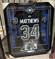 Full front view of framed display showing signed jersey, puck, photo and plaque