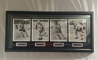 Framed group photo print with four signed images of hockey players under glass in black frame.