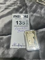 Bar coin and MaxSold note card on grey fabric