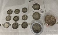 Photo showing 12 Canadian silver coins from the early 1900s: 3 quarters and 9 dimes, some in holders and cases.