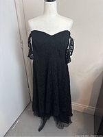 Black off-shoulder lace dress displayed on mannequin