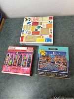 Three boxed puzzles arranged on table, showing different designs: Ottawa at night, Coca-Cola bottles, and a colorful collage.