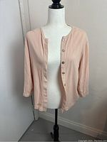 Light peach 3/4 sleeve button-up cardigan on mannequin showing front view