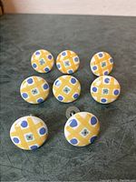 Photo of 8 ceramic drawer knobs arranged on a surface showing the colorful pattern on the front.
