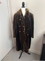 Full view of the long dark brown beaver fur coat on a mannequin showing double-breasted style and buttons.