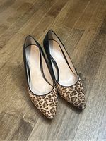 Front angle photo showing pointed toe animal print suede front with black leather sides and heel, worn condition visible on outer toe area.