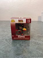 Front view of unopened Funko Pop Minis Deadpool figure number 13 in Marvel Zombies series inside red box with clear window.