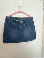 Front view of Levi's blue denim mini skirt on pink hanger.