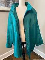 Front view of the vintage emerald green windbreaker coat displayed on a mannequin showing the collar, button closure, and relaxed fit.