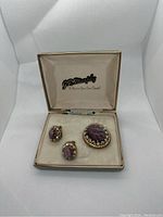 Brooch and two earrings set inside an open cream velvet GR Murphy jewelry box.