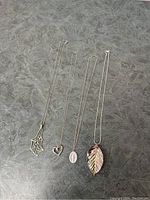 Four necklaces laid out individually with pendants facing forward, showing design details