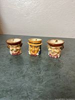 Front view of three Toby mugs showing facial features and hat designs.