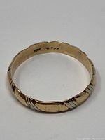 Close-up photo of ring showing interior stamp '10K' and the detailed twisted two-tone gold design on the band.