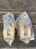 Two Campbell block pulleys sealed in plastic showing wooden frames and metal hooks