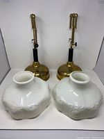 Two Coleman Quick-Lite lamp bases and two milk glass shades from front view
