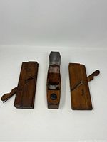 Three antique wooden hand planes displayed side-by-side showing top view with visible blades and handles