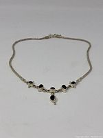 Full view of the necklace showing the black bead design on the front centerpiece and silver chain extending either side.