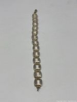 Full length view of the silver chain bracelet laid flat on a white background, showing the open link design and lobster clasp.