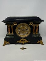 Frontal view of entire clock on white background with winding key laid in front