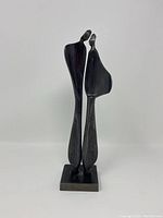Front view of the abstract sculpture showing two tall slender figures close together on a rectangular base