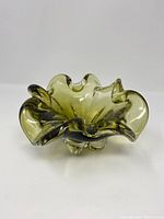 Photo of vintage green chalet glass bowl showing ruffled edges, thick base, and translucent olive green glass with a stamped mark.