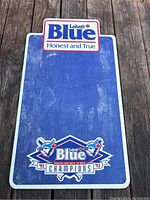 Full front view of rectangular blue chalkboard with Labatt Blue logo at top and Toronto Blue Jays 1992-93 champions logo at bottom on a wood surface.
