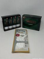 Front view of 2 boxes of Precept LADDIE golf balls and 1 pack of Callaway CX golf gloves