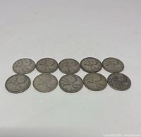 Ten Canadian silver quarters arranged in two rows on a white background, showing the reverse side with caribou.