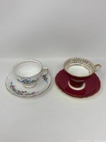 Front view of two teacup and saucer sets side by side, showing decoration and color of each cup and saucer.