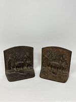 Pair of cast iron bookends with pirate relief, front view showing two pirates carrying a treasure chest.