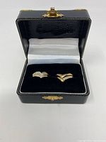 Two gold tone V-shaped dip design rings displayed in a black hinged box with gold clasp and velvet interior.