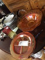 Table display of two divided plates and one red-amber vase with greenish ribs, showing distinct Amberina coloring and translucency.