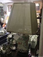 Lamp showing stained fabric shade and painted ceramic base with Asian style design.